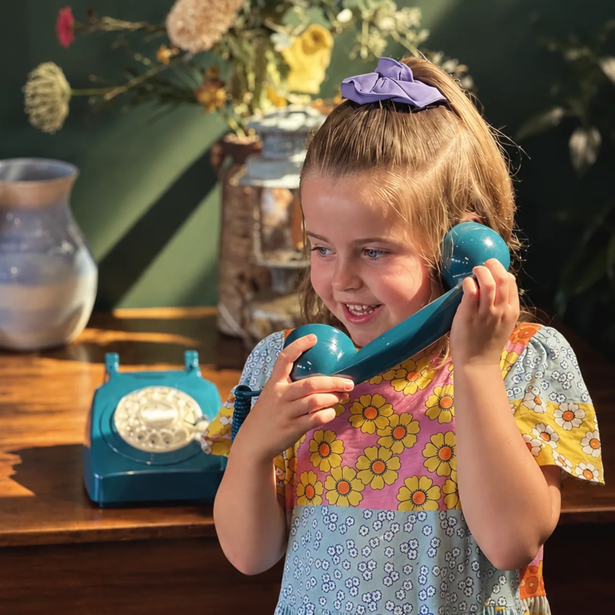 A girl talking on a teal rotary phone
